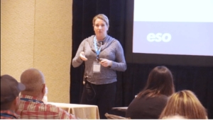 A woman giving a presentation in front of a crowd of people at ESO Wave 2018.