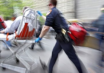 A paramedic quickly pushing a patient on a gurney.