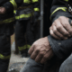 Image of worn firefighter's hands in uniform, sitting over to the side.