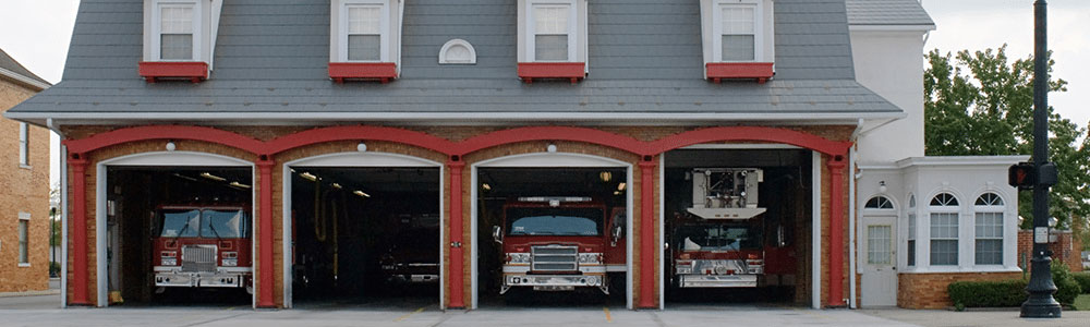 front entrance of firehouse with open bays and firetrucks lined up inside