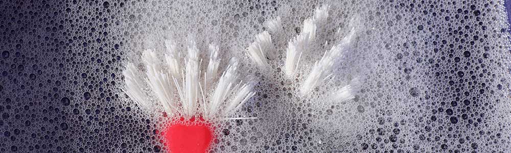 two dish scrubbers floating in sink with soapy water
