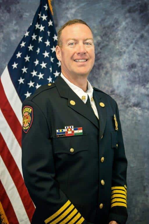 Headshot of Bill Gardner in uniform in front of American flag.