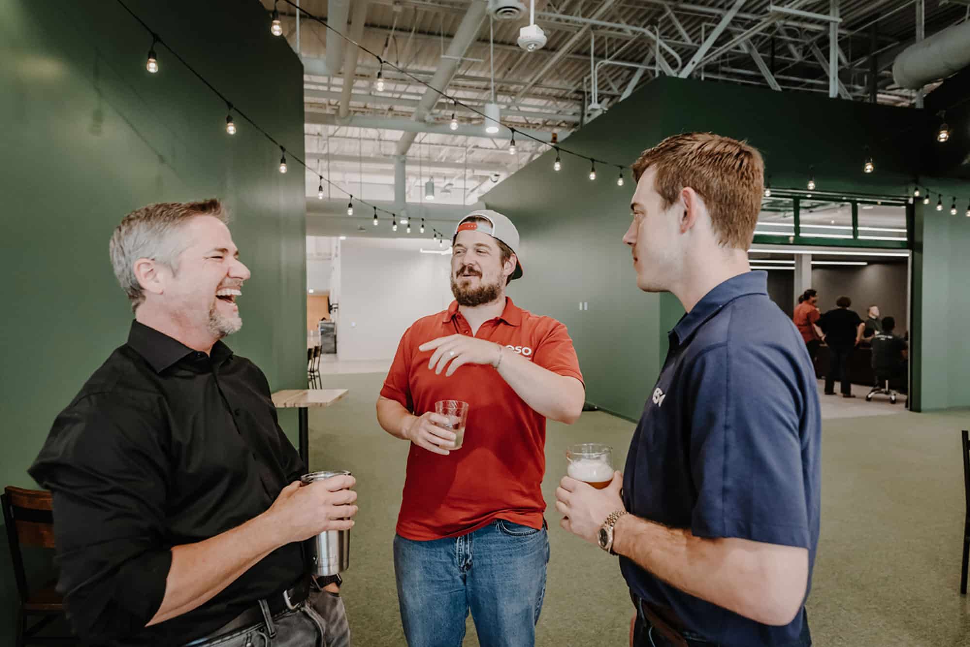 Three men laughing and chatting at an ESO quarterly happy hour.