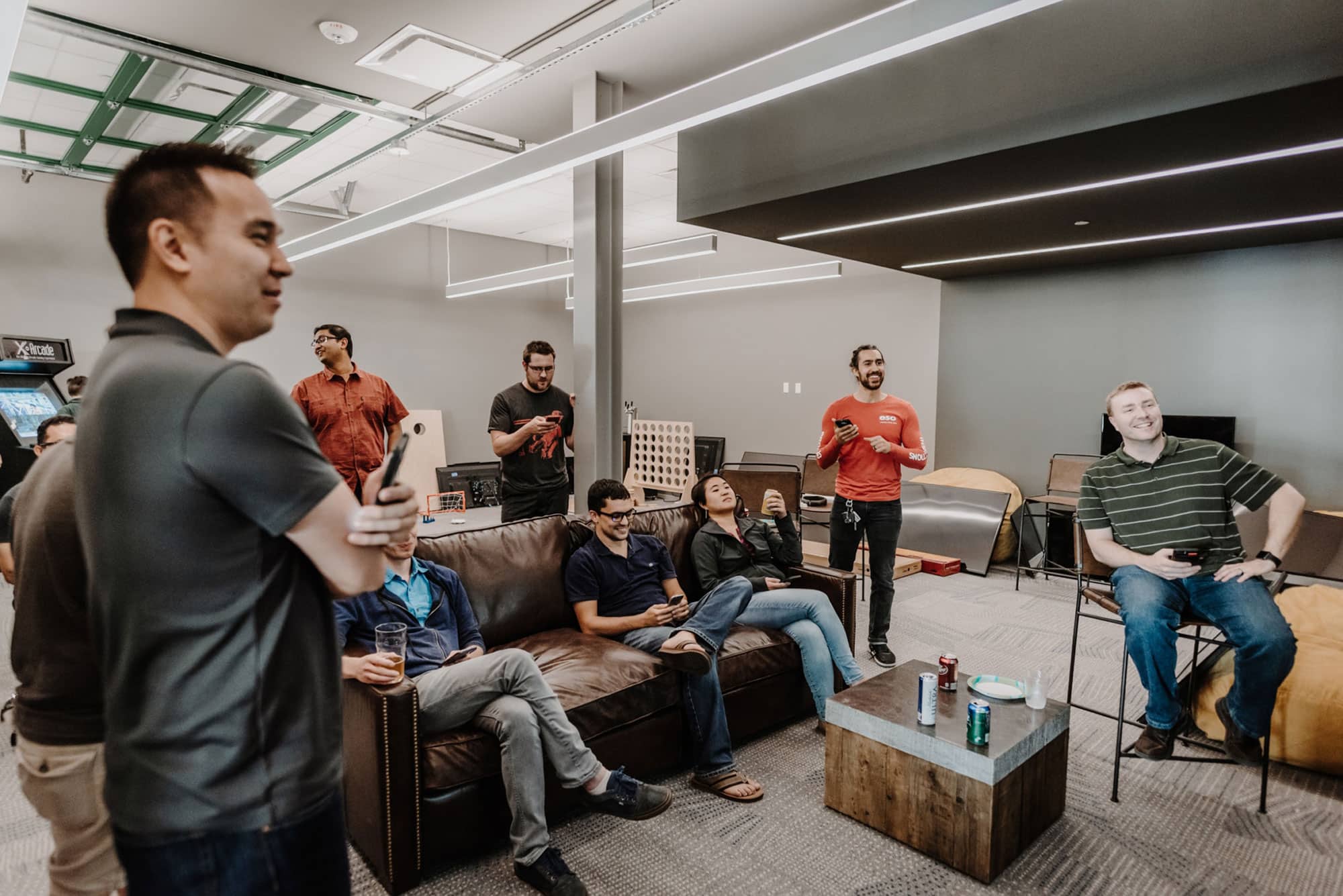 A group of coworkers sitting around an office lounge room chatting and relaxing.