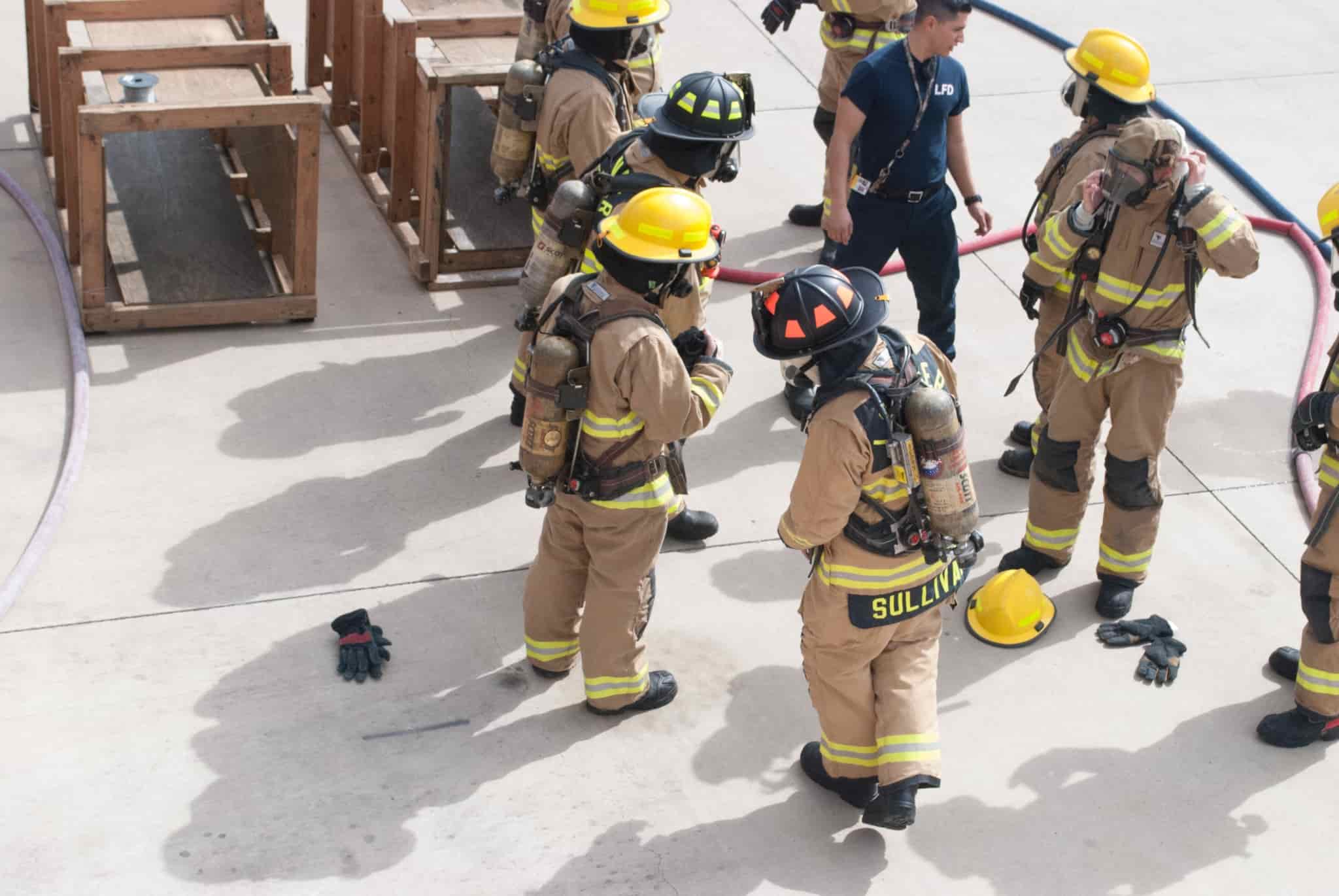 A group of firefighters standing around each other during training.