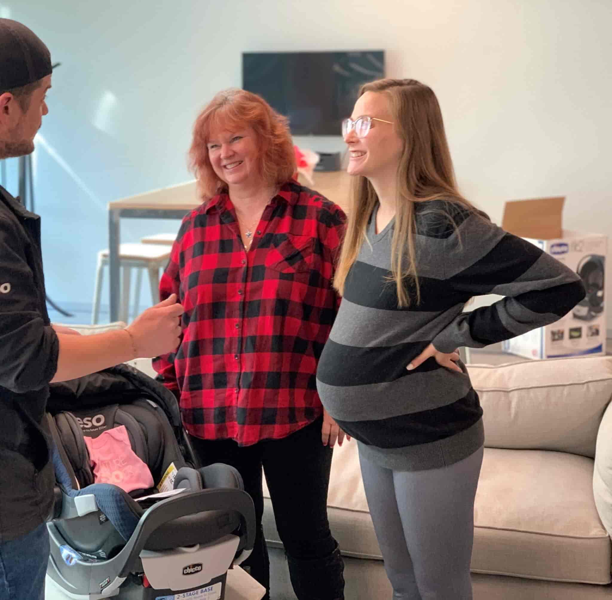 An ESO instructor demonstrating child car seat safety to two pregnant women.