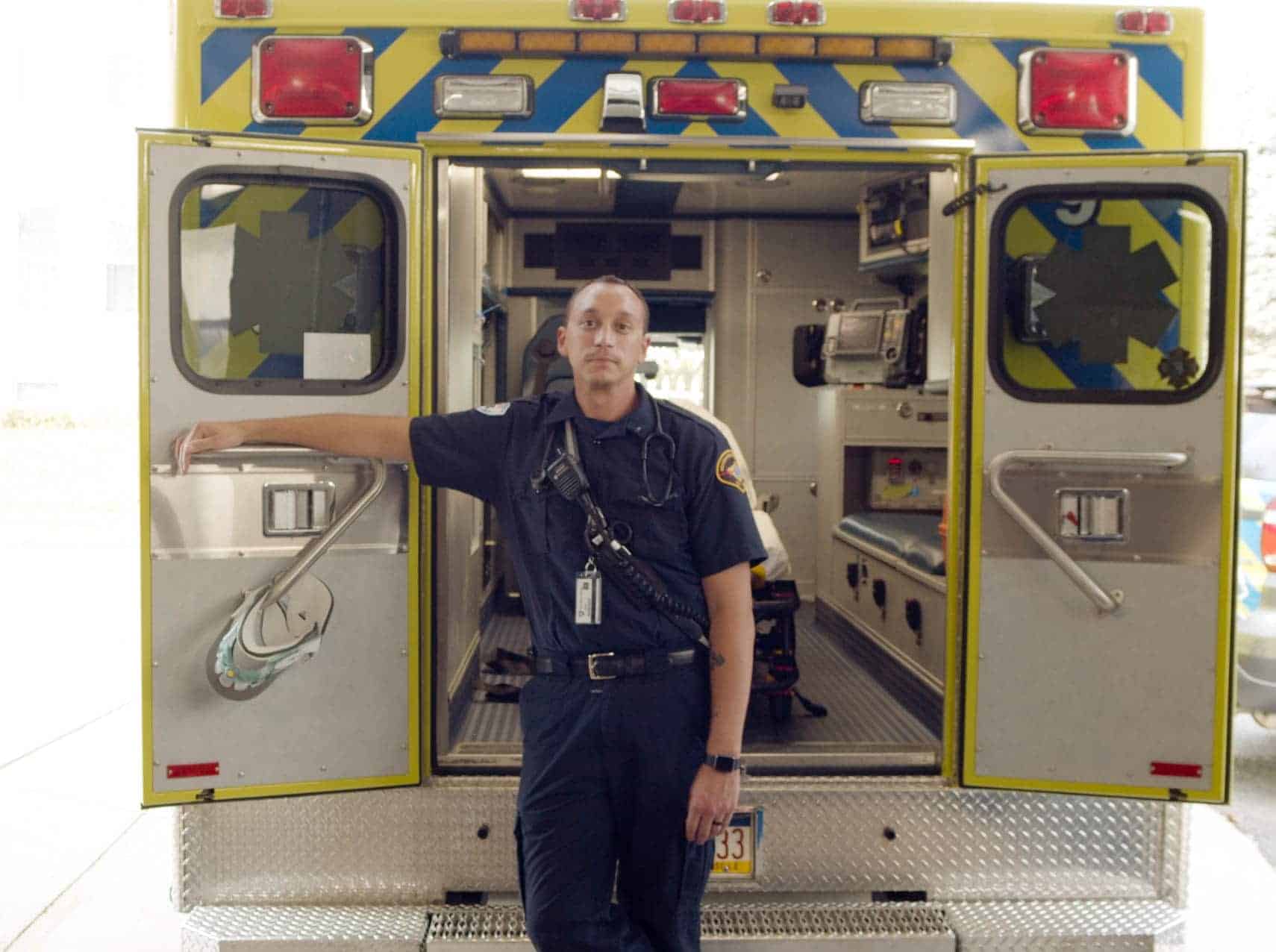 A paramedic standing in the open rear doors of an ambulance.