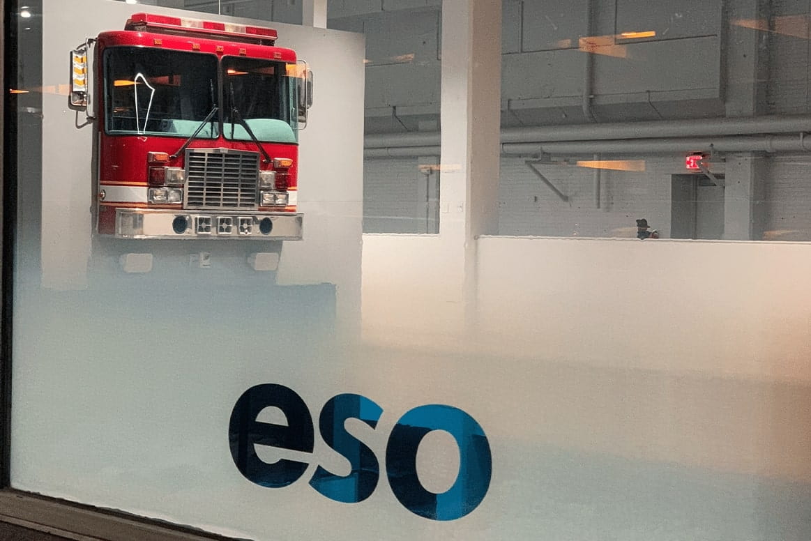 The ESO logo on the exterior of an office building with a fire truck in background.